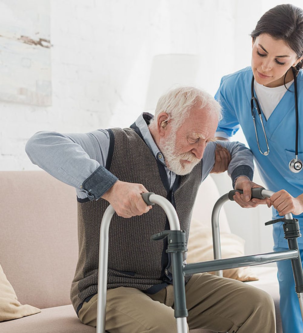 Doctor helping to retired man, getting up from sofa